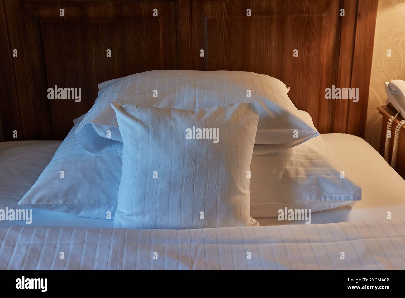 Lit d'hôtel avec draps blancs, éclairage confortable Banque D'Images