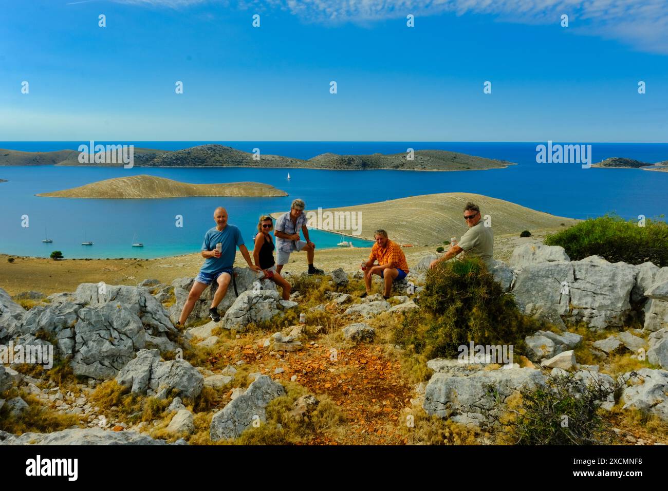 Un groupe de personnes est assis sur une colline rocheuse surplombant l'océan. La scène est paisible et sereine, car le groupe profite de la belle vue sur l'eau Banque D'Images