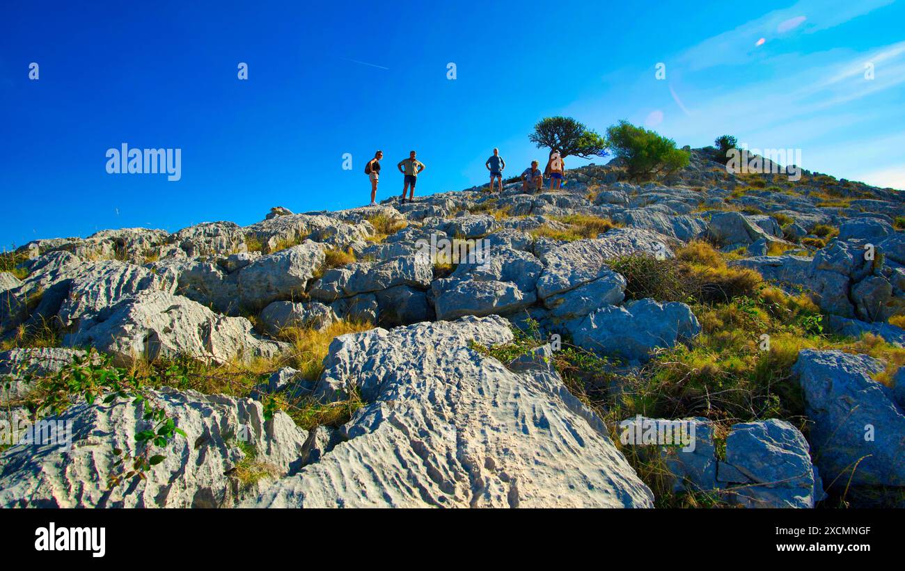 Un groupe de personnes se tient sur une colline rocheuse, regardant au-dessus du paysage. La scène est paisible et contemplative, comme le groupe semble être taki Banque D'Images