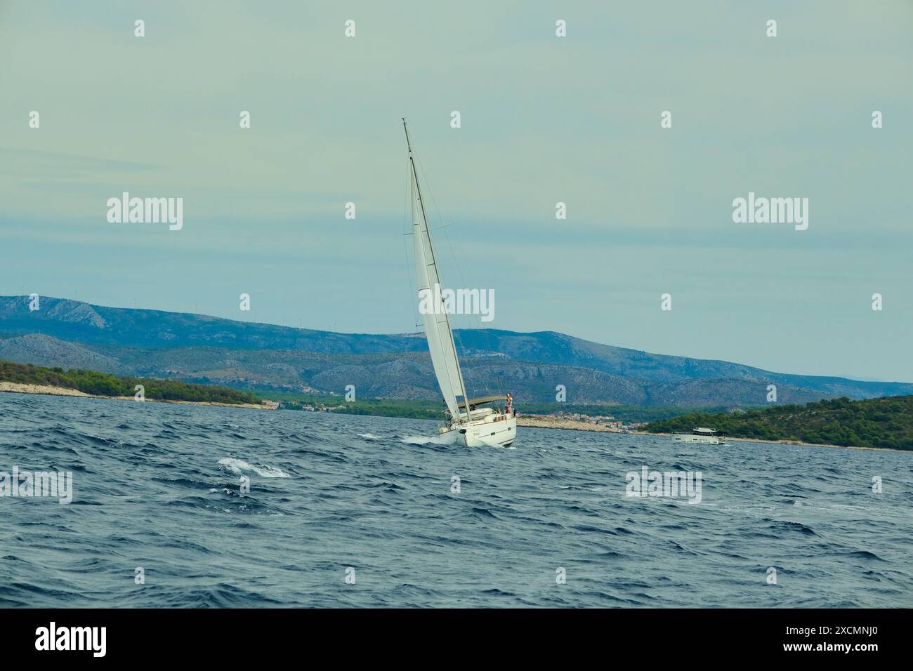 Un voilier navigue sur l'océan avec un ciel bleu clair en arrière-plan. Le voilier est le seul objet visible sur l'image Banque D'Images