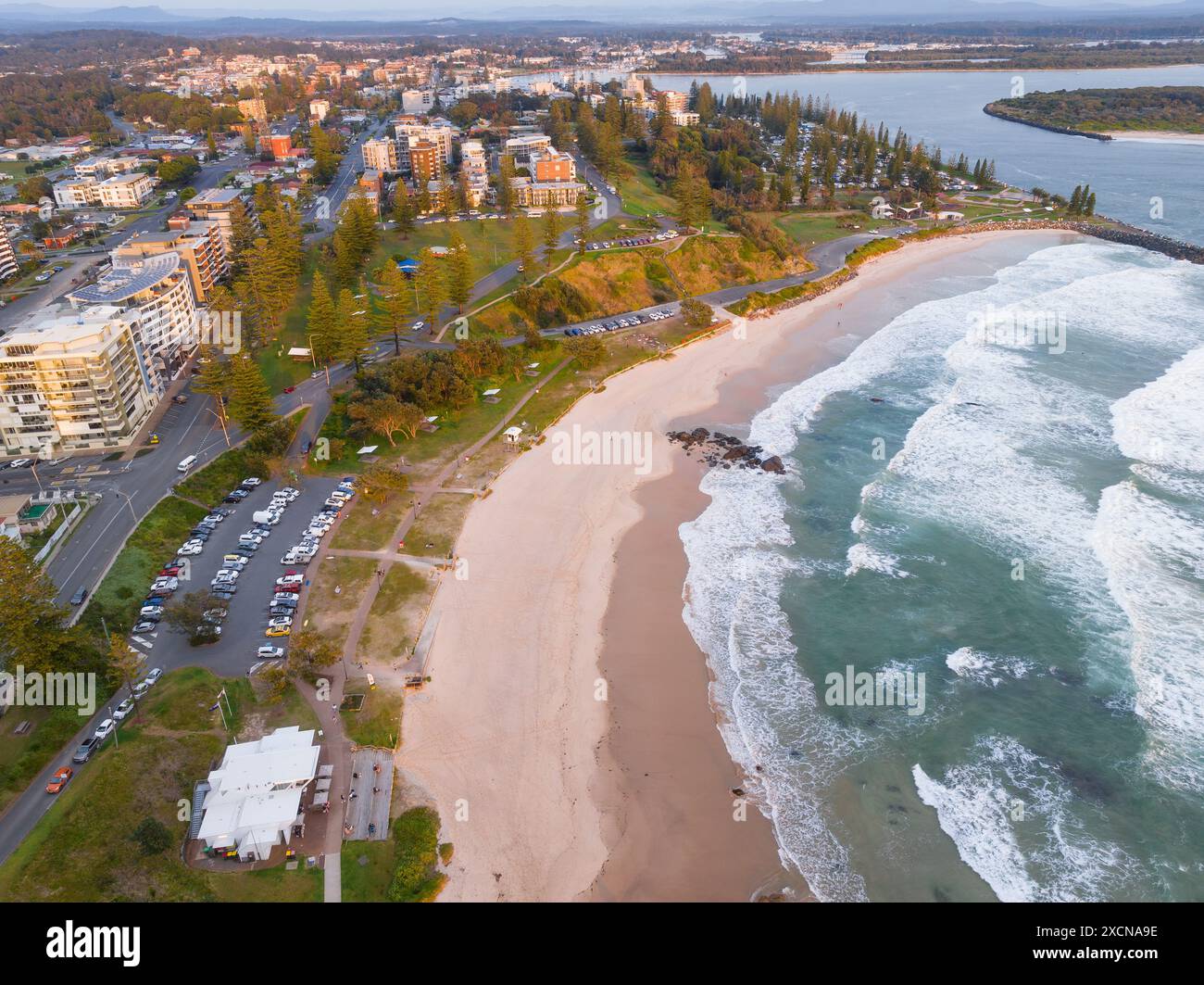 Vue aérienne sur une longue plage de sable sous les bâtiments d'une ville côtière sous le soleil tôt le matin à Port Macquarie en Nouvelle-Galles du Sud Banque D'Images