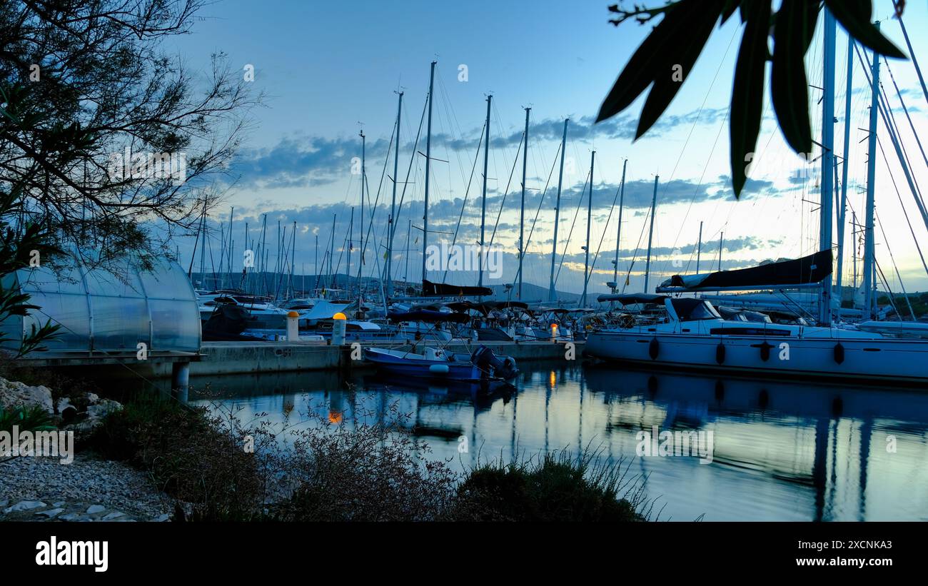 Un groupe de bateaux est amarré à une marina, avec le coucher de soleil en arrière-plan Banque D'Images