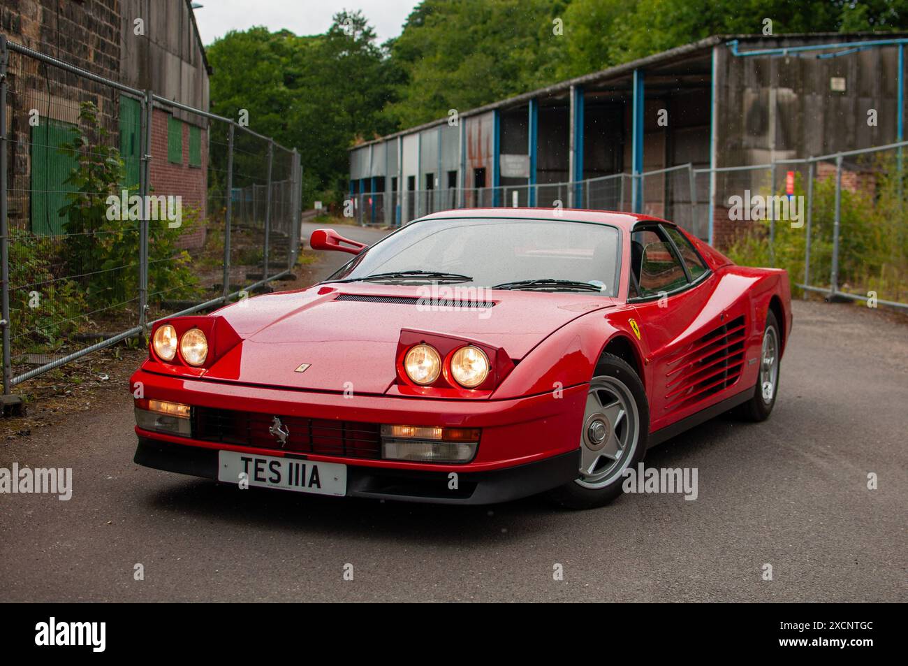 Une Ferrari Testarossa des années 80 se dresse avec ses phares escamotables dans un complexe industriel désaffecté. Banque D'Images