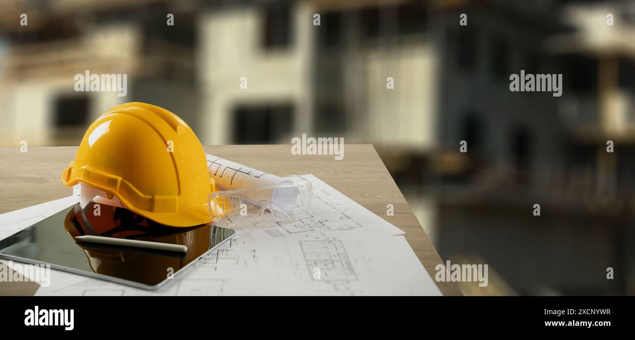 Yellow HardHat, équipement de sécurité essentiel pour les ouvriers de la construction et les architectes, se trouve à côté des plans présentant les plans de construction Banque D'Images