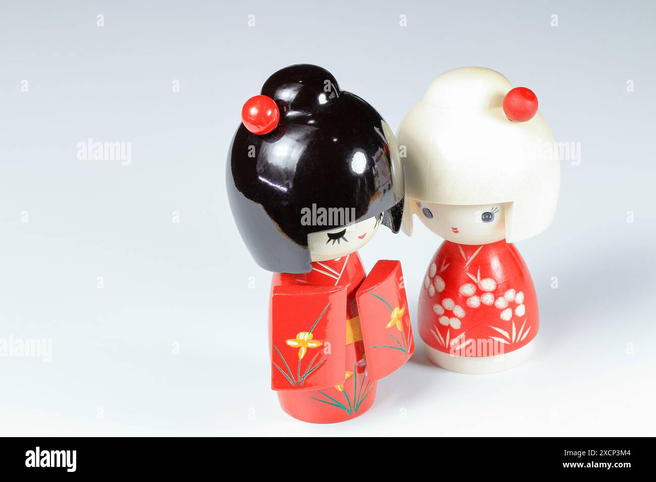 Poupées japonaises en bois 'kokeshi' en costume kimono rouge, jouet pour une décoration, souvenir du Japon isolé sur fond blanc. Banque D'Images