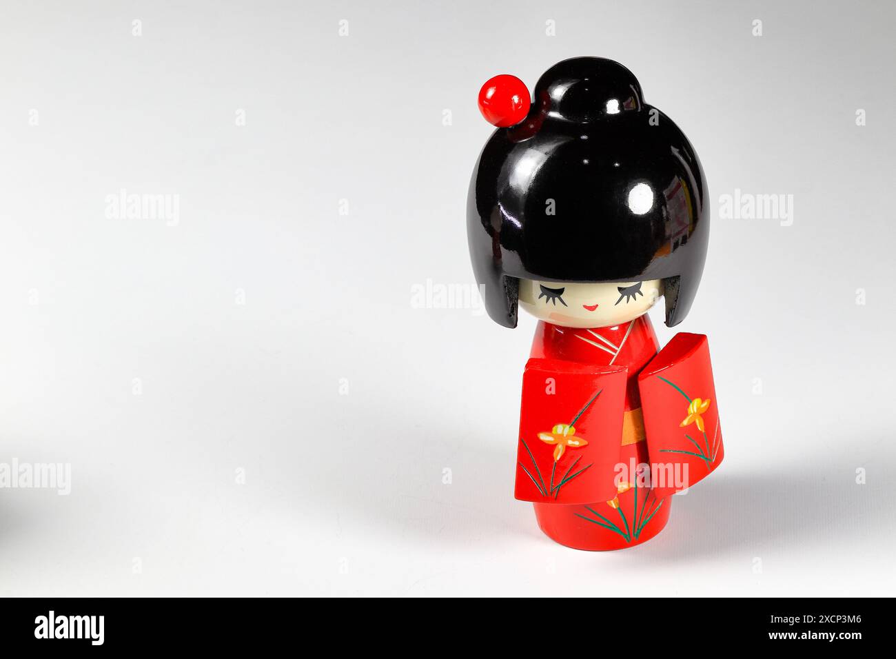 Poupées japonaises en bois 'kokeshi' en costume kimono rouge, jouet pour une décoration, souvenir du Japon isolé sur fond blanc. Banque D'Images