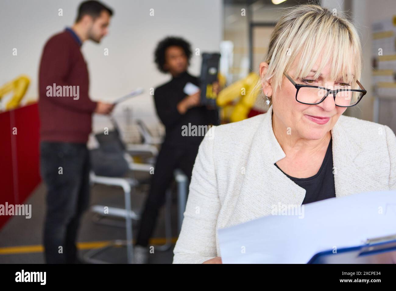 Groupe de professionnels engagés dans la formation et la programmation robotique, se concentrant sur l'automatisation des processus, montrant le travail d'équipe dans un environnement industriel. Banque D'Images