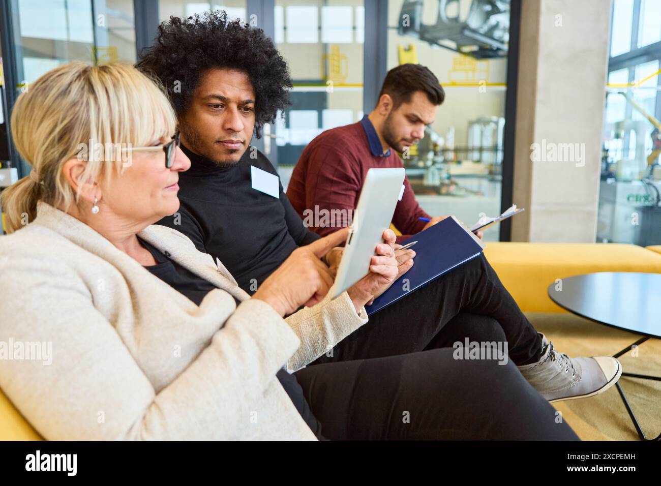 Trois collègues collaborent à la programmation et au développement robotiques dans un espace de bureau moderne, discutant des processus d'automatisation et de la technologie innova Banque D'Images