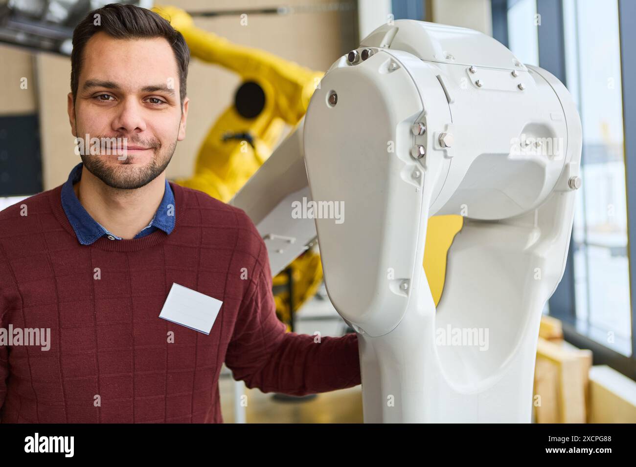 Ingénieur avec un bras robotisé dans un environnement industriel, mettant en évidence la robotique, l'automatisation, la programmation et l'automatisation des processus dans diverses industries. Banque D'Images