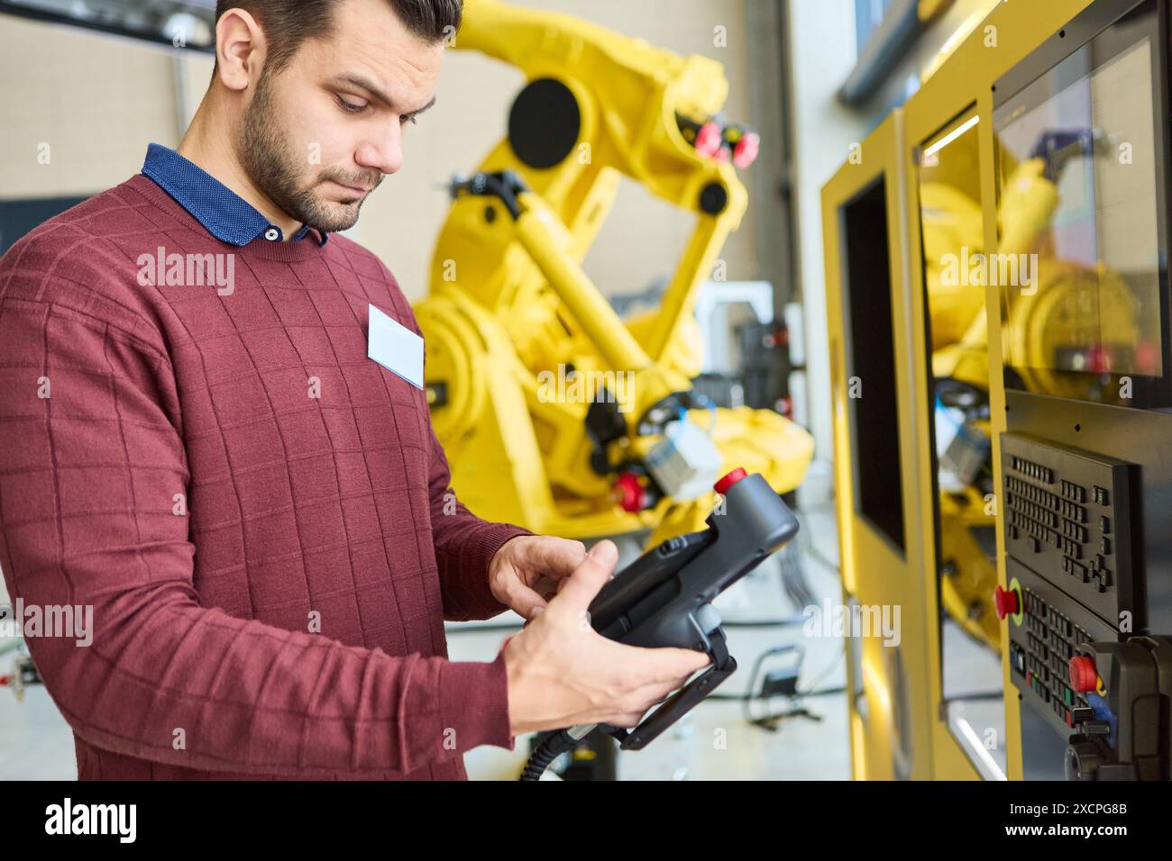 Ingénieur travaillant sur la programmation d'un robot industriel avec un bras de préhension en usine, se concentrant sur la production automatisée et la technologie robotique. Banque D'Images