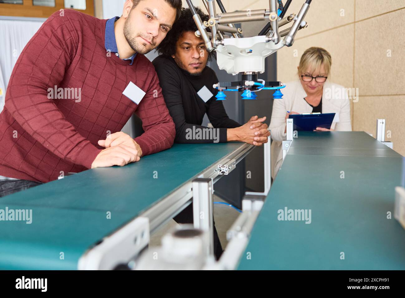 Groupe de personnes observant et apprenant sur les bras robotiques avancés conçus pour la production et les applications industrielles. Banque D'Images