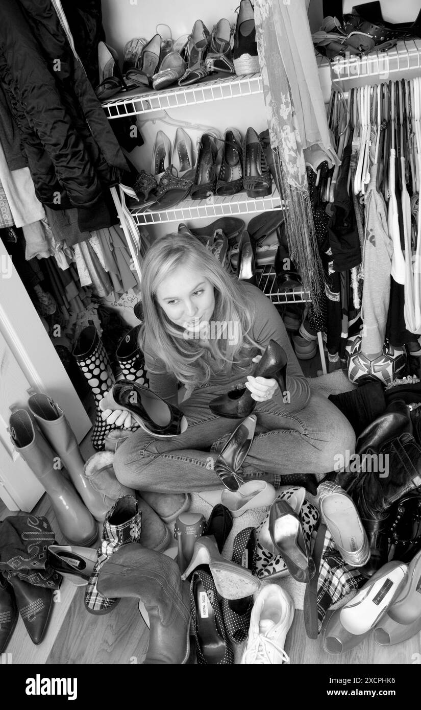 Jolie adolescente cente caucasienne choisissant des chaussures à porter de son placard, USA. Banque D'Images