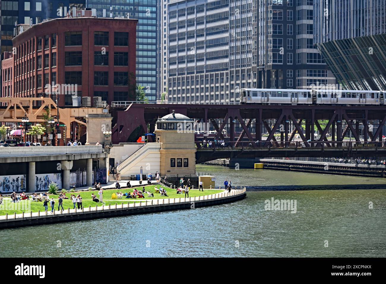 Les gens se détendent sur la section herbeuse du Riverwalk près du Lake Street Bridge où les trois branches de la rivière Chicago se croisent au centre-ville. Banque D'Images