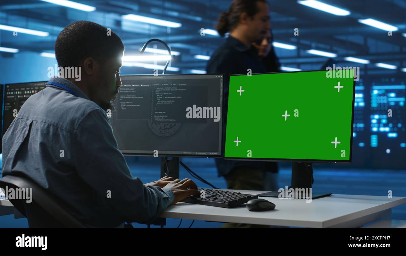 Programmeur codant sur l'ordinateur d'écran isolé dans le centre de données, supervisant les rangées de serveurs dans le centre de données de sécurité de réseau informatique. Technicien INFORMATIQUE supervisant les superordinateurs à l'aide d'un moniteur PC Chroma Key Banque D'Images