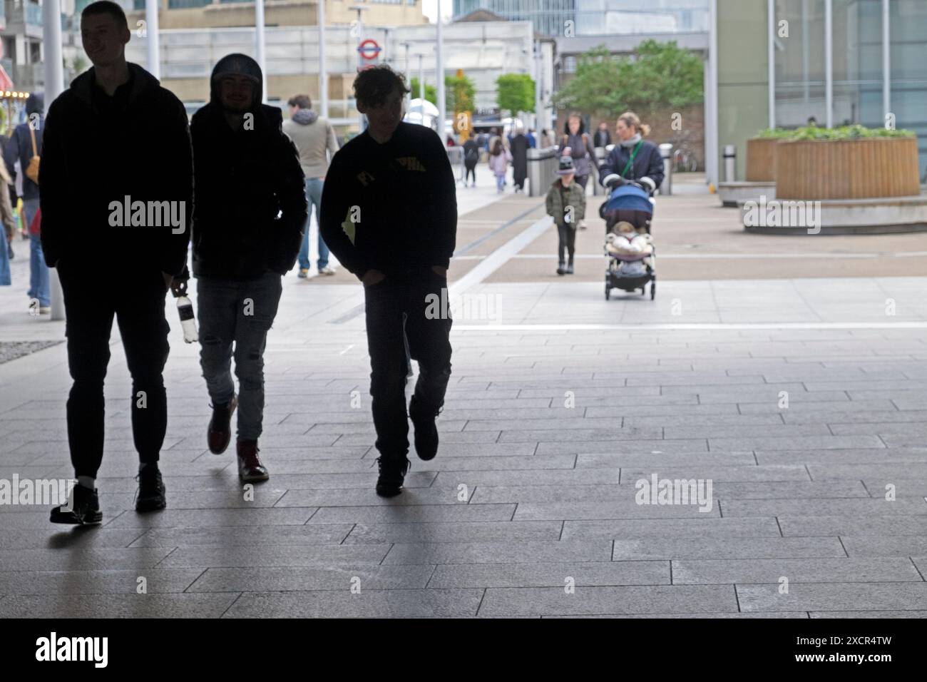 Silhouettes de jeunes hommes marchant sous le pont du bassin de Paddington devant la gare de Londres Angleterre Royaume-Uni 2024 Grande-Bretagne KATHY DEWITT Banque D'Images