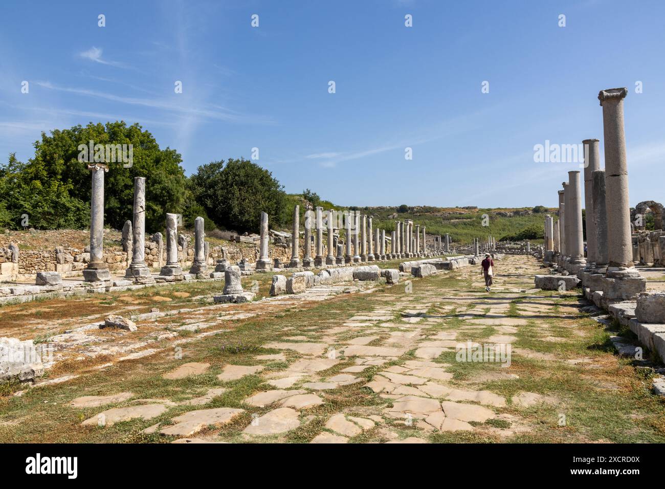 Une femme marchant dans la rue colonnade avec des dizaines de colonnes dans l'ancienne ville en ruines de Perge près d'Antalya en Turquie par une belle journée ensoleillée. Banque D'Images