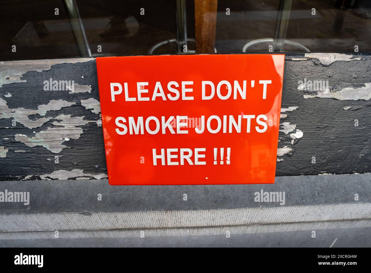 Une pancarte sur un banc à l'extérieur d'un café fumant du cannabis à Amsterdam, aux pays-Bas, indique : « S'il vous plaît ne fumez pas les joints ici » Banque D'Images