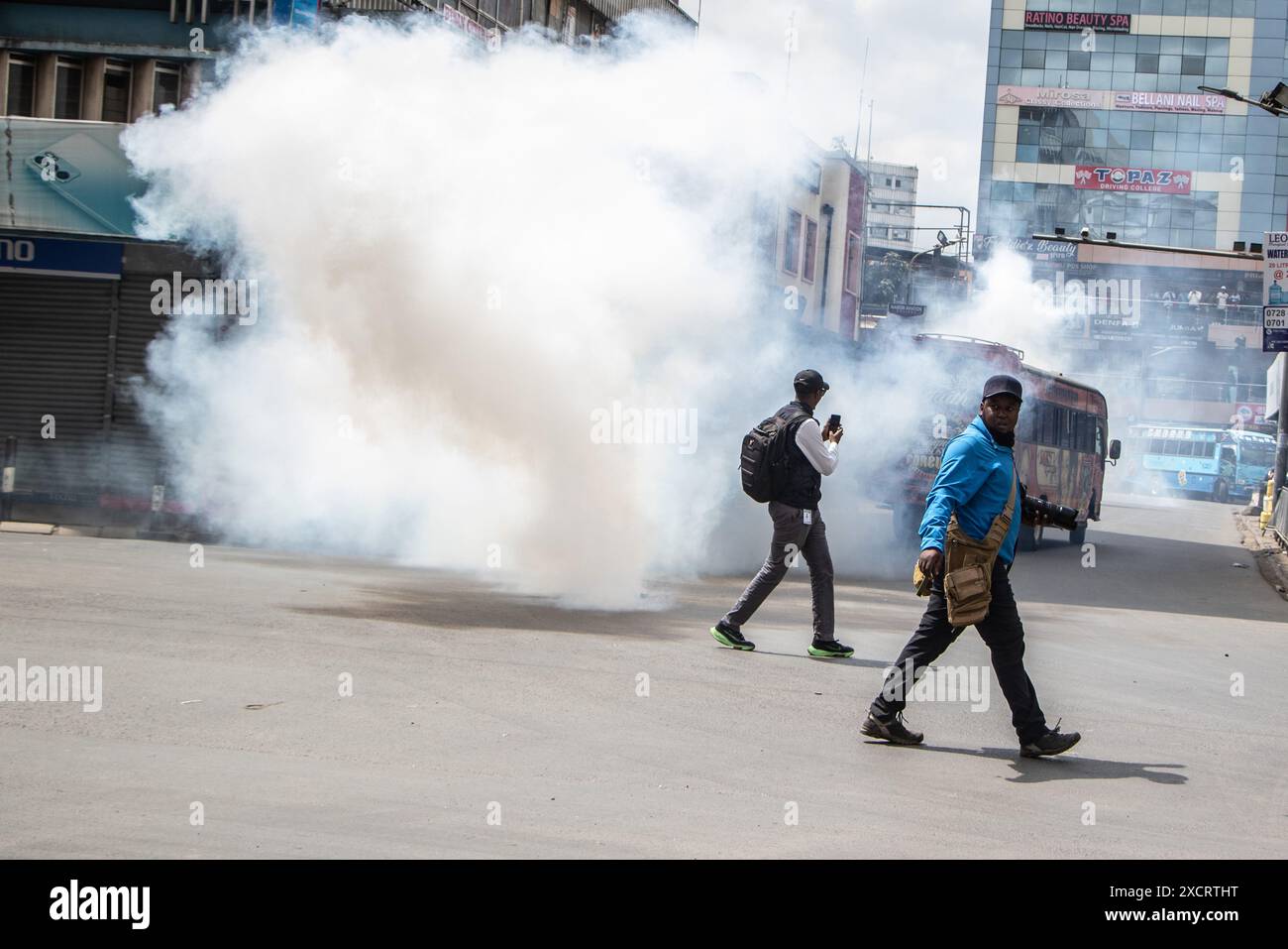 Nairobi, Kenya. 18 juin 2024. Des journalistes passent devant un nuage de fumée provenant d'une cartouche lacrymogène lors d'une manifestation contre le projet de loi de finances 2024 dans les rues de Nairobi. Le projet de loi propose plusieurs nouvelles taxes, dont une taxe de circulation sur les véhicules automobiles, une taxe sur les transferts de fonds, une taxe écologique et des droits d'accise sur le pain et l'huile de cuisson. La manifestation baptisée #RejectTheFinanceBill2024 a lieu alors que le projet de loi est déposé, avec des manifestants exhortant les membres du parlement à rejeter les dispositions litigieuses. Crédit : SOPA images Limited/Alamy Live News Banque D'Images