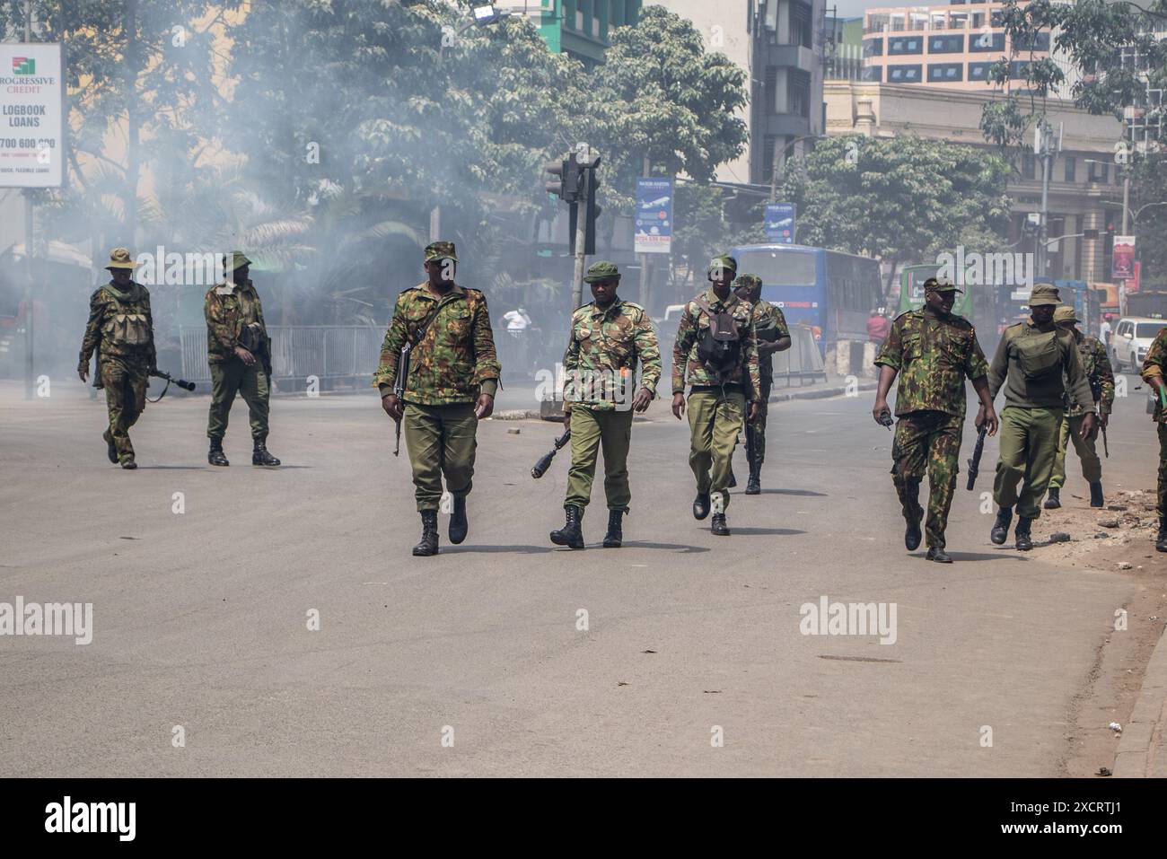 Nairobi, Kenya. 18 juin 2024. Des policiers anti-émeutes passent devant un nuage de fumée provenant d’une cartouche lacrymogène lors d’une manifestation contre le projet de loi de finances 2024 dans les rues de Nairobi. Le projet de loi propose plusieurs nouvelles taxes, dont une taxe de circulation sur les véhicules automobiles, une taxe sur les transferts de fonds, une taxe écologique et des droits d'accise sur le pain et l'huile de cuisson. La manifestation baptisée #RejectTheFinanceBill2024 a lieu alors que le projet de loi est déposé, avec des manifestants exhortant les membres du parlement à rejeter les dispositions litigieuses. Crédit : SOPA images Limited/Alamy Live News Banque D'Images