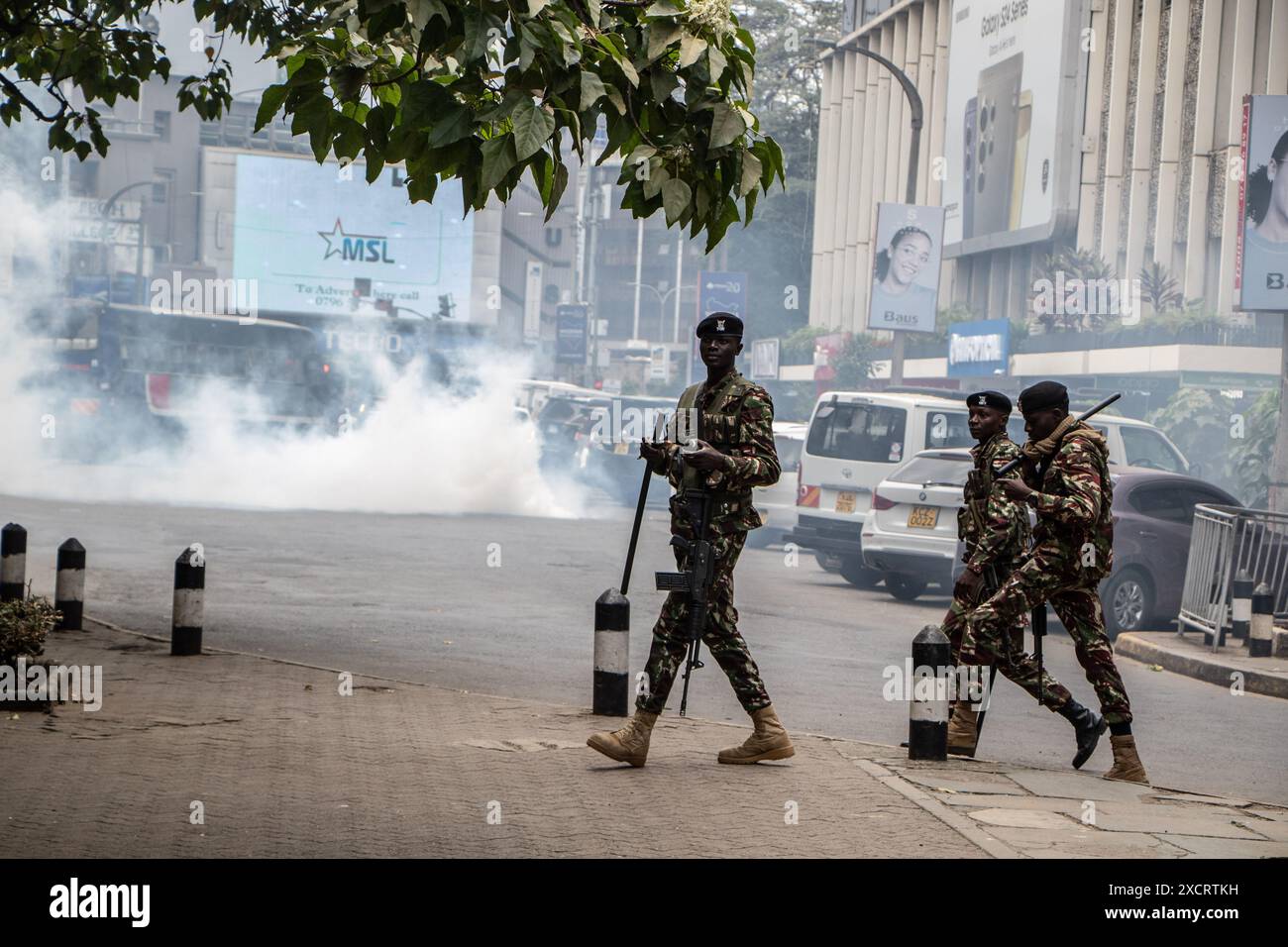 Nairobi, Kenya. 18 juin 2024. Des policiers anti-émeutes passent devant un nuage de fumée provenant d’une cartouche lacrymogène lors d’une manifestation contre le projet de loi de finances 2024 dans les rues de Nairobi. Le projet de loi propose plusieurs nouvelles taxes, dont une taxe de circulation sur les véhicules automobiles, une taxe sur les transferts de fonds, une taxe écologique et des droits d'accise sur le pain et l'huile de cuisson. La manifestation baptisée #RejectTheFinanceBill2024 a lieu alors que le projet de loi est déposé, avec des manifestants exhortant les membres du parlement à rejeter les dispositions litigieuses. Crédit : SOPA images Limited/Alamy Live News Banque D'Images