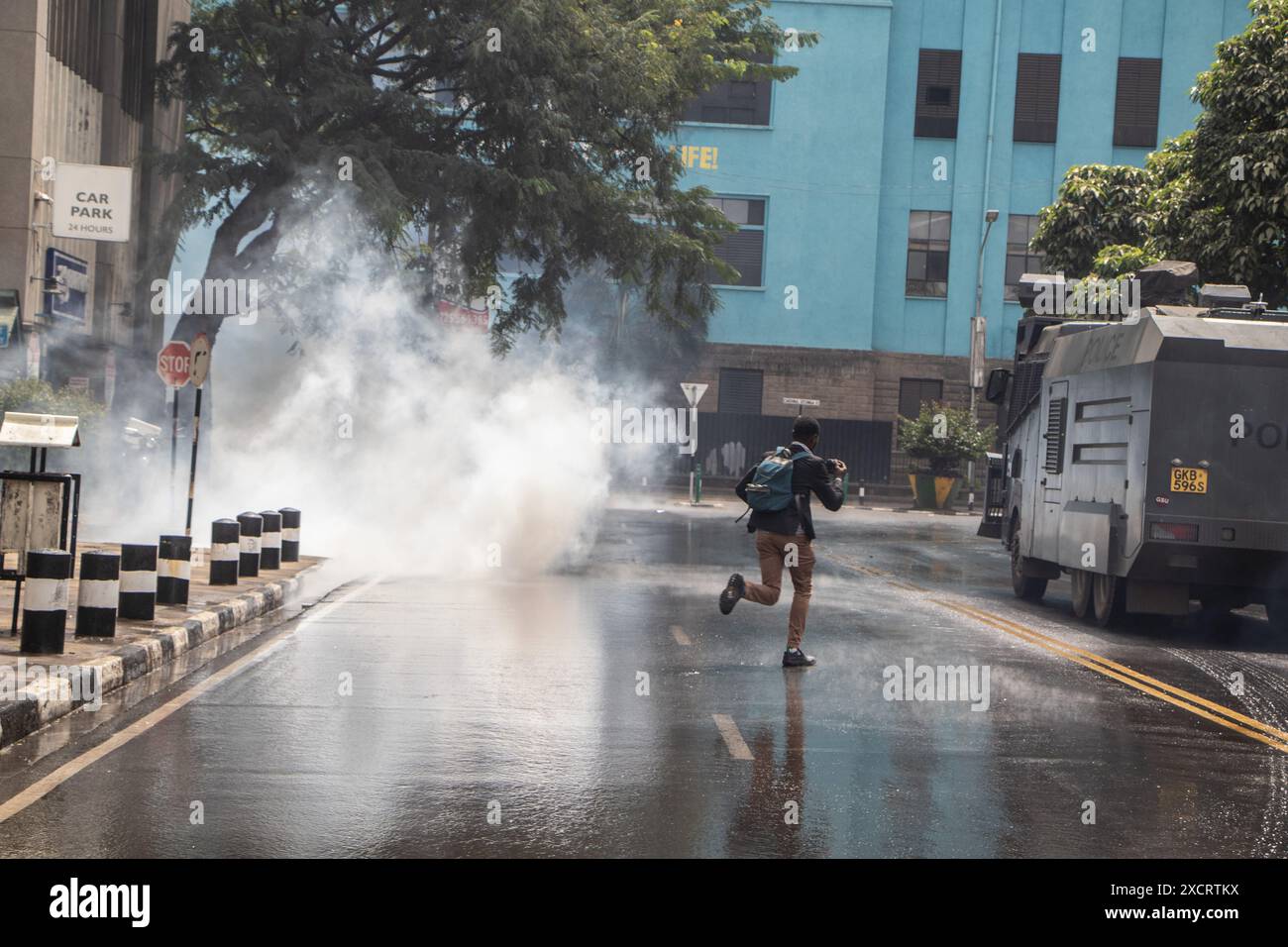Nairobi, Kenya. 18 juin 2024. Un journaliste court devant un canon à eau de la police dispersant les manifestants lors d'une manifestation contre le projet de loi de finances 2024 dans les rues de Nairobi. Le projet de loi propose plusieurs nouvelles taxes, dont une taxe de circulation sur les véhicules automobiles, une taxe sur les transferts de fonds, une taxe écologique et des droits d'accise sur le pain et l'huile de cuisson. La manifestation baptisée #RejectTheFinanceBill2024 a lieu alors que le projet de loi est déposé, avec des manifestants exhortant les membres du parlement à rejeter les dispositions litigieuses. Crédit : SOPA images Limited/Alamy Live News Banque D'Images