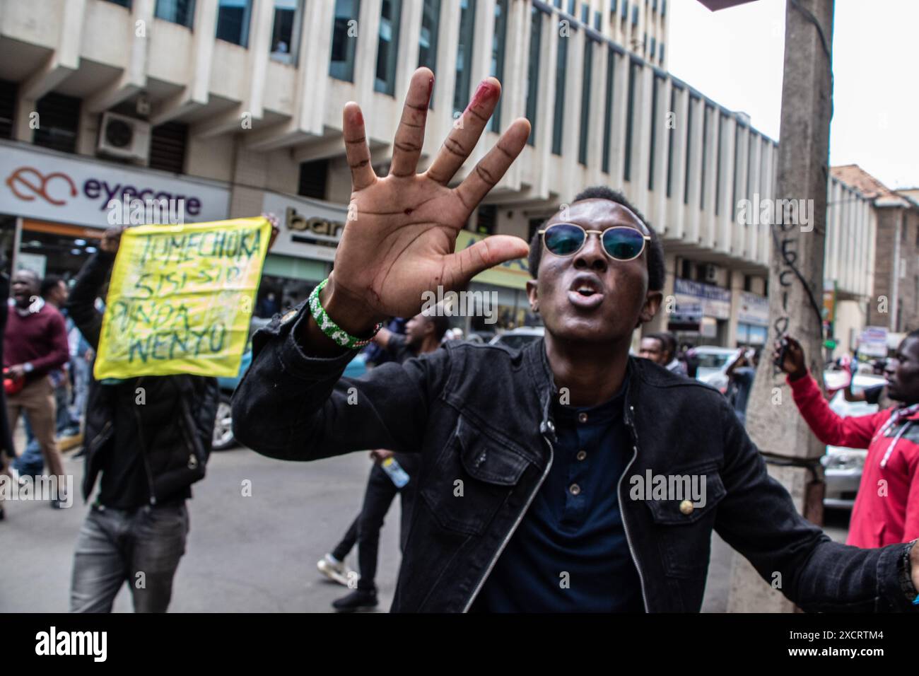 Nairobi, Kenya. 18 juin 2024. Un manifestant fait des gestes tout en montrant sa main blessée après que la police ait fait pression sur des cartouches lacrymogènes contre les manifestants lors d'une manifestation contre le projet de loi de finances 2024 dans les rues de Nairobi. Le projet de loi propose plusieurs nouvelles taxes, dont une taxe de circulation sur les véhicules automobiles, une taxe sur les transferts de fonds, une taxe écologique et des droits d'accise sur le pain et l'huile de cuisson. La manifestation baptisée #RejectTheFinanceBill2024 a lieu alors que le projet de loi est déposé, avec des manifestants exhortant les membres du parlement à rejeter les dispositions litigieuses. Crédit : SOPA images Limited/Alamy Live News Banque D'Images