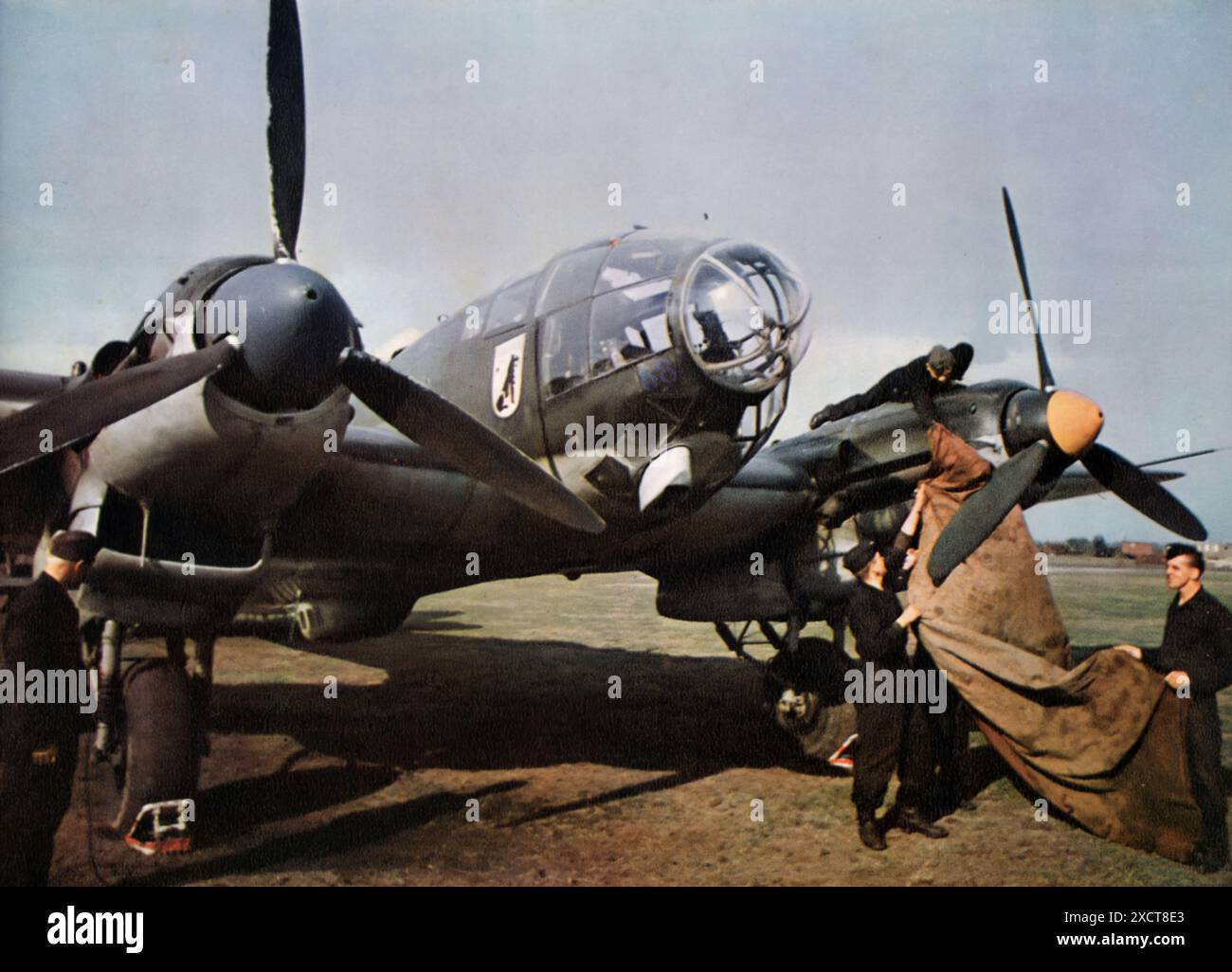 Une photographie montre des soldats de l'armée de l'air allemande (Luftwaffe) enlevant les couvertures d'un avion alors qu'ils se préparent à un vol pendant la seconde Guerre mondiale. Cette scène capture la préparation et l'entretien nécessaires pour s'assurer que l'avion est prêt pour sa mission. Banque D'Images