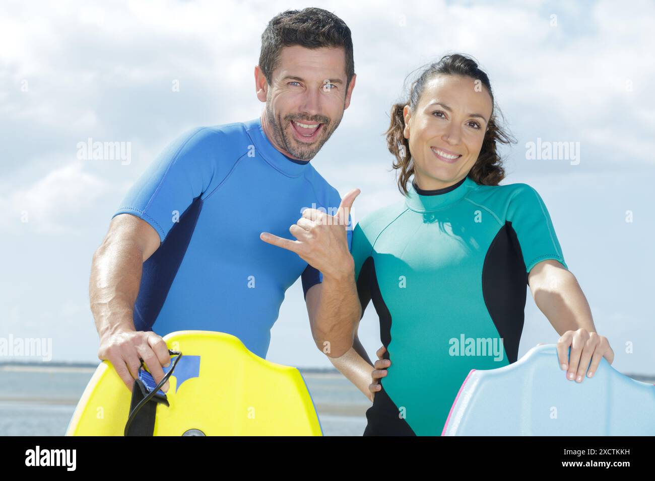 couple heureux avec boogie-boards faisant accrocher le geste lâche Banque D'Images