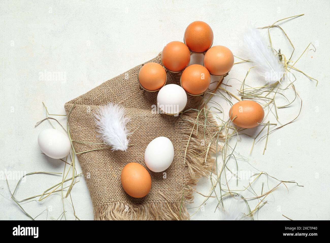 Support avec des œufs de poule crus et sac de tissu sur fond blanc Banque D'Images