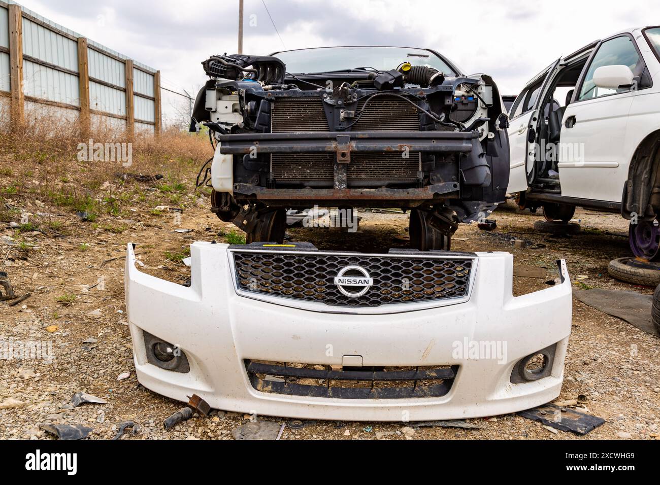 Le carénage blanc du pare-chocs avant d'une Nissan Sentra se trouve devant une voiture usagée au LKQ Pick Your part Scrapyard à Fort Wayne, Indiana, États-Unis. Banque D'Images