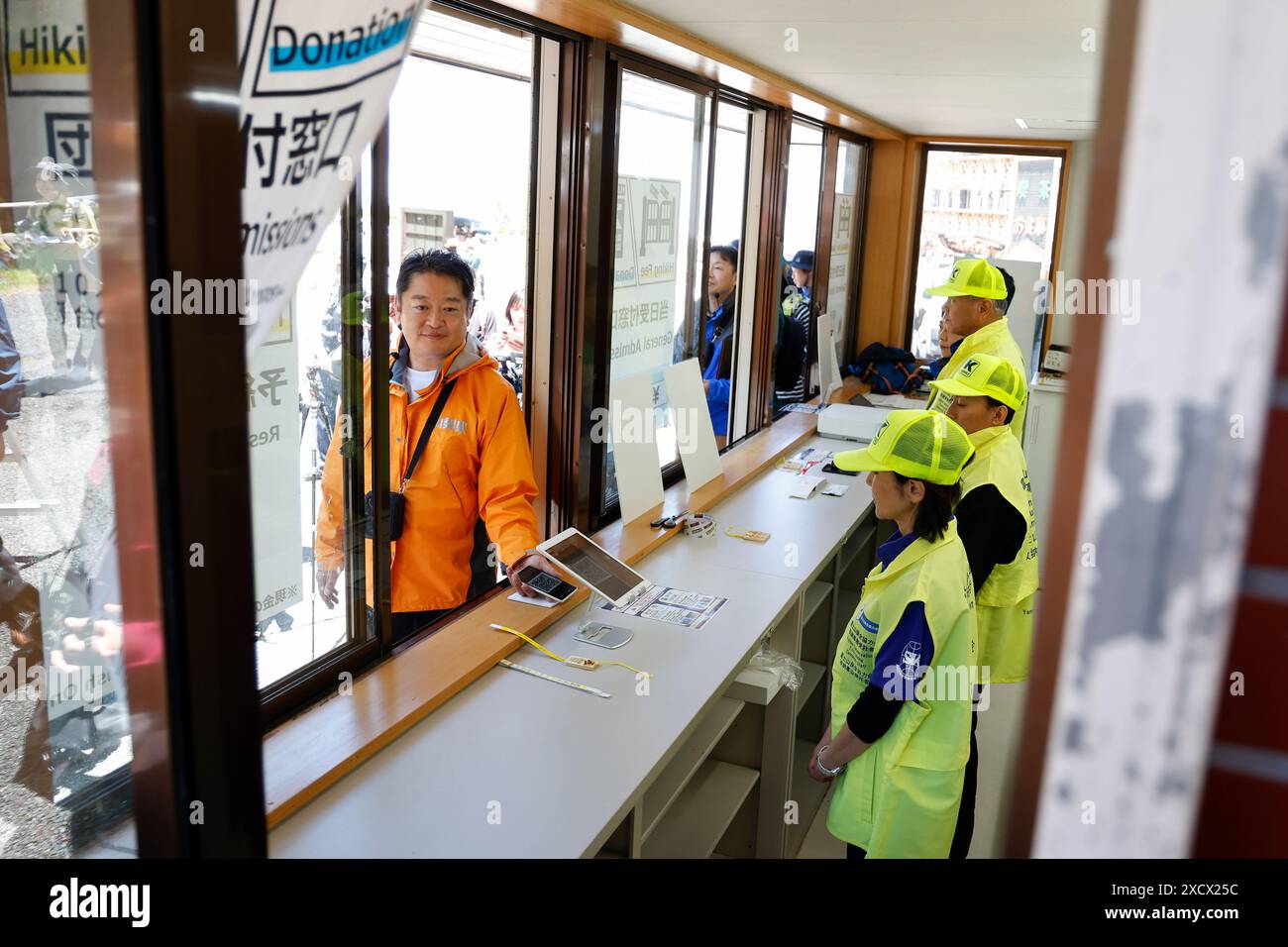 19 juin 2024, district de Minamitsuru, Yamanashi, Japon : Kotaro Nagasaki gouverneur de Yamanashi scanne son code QR de réservation au 5e centre d'administration de la ligne Fuji Subaru, le point de départ le plus populaire pour gravir le mont Fuji. Le gouverneur Nagasaki a participé à une répétition en tant qu'alpiniste, montrant aux médias le fonctionnement actuel de la 5e station, y compris la collecte des droits d'entrée pour les grimpeurs. À partir de cette année, les autorités mettront en œuvre de nouvelles mesures telles qu’une limite de 4000 grimpeurs par jour, une augmentation des frais d’accès et un service à durée limitée. La saison de randonnée commence du 1er juillet à Septembe Banque D'Images
