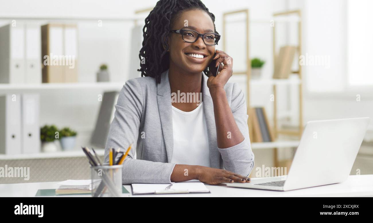 Femme afro-américaine gérant des tâches sur ordinateur portable au bureau Banque D'Images