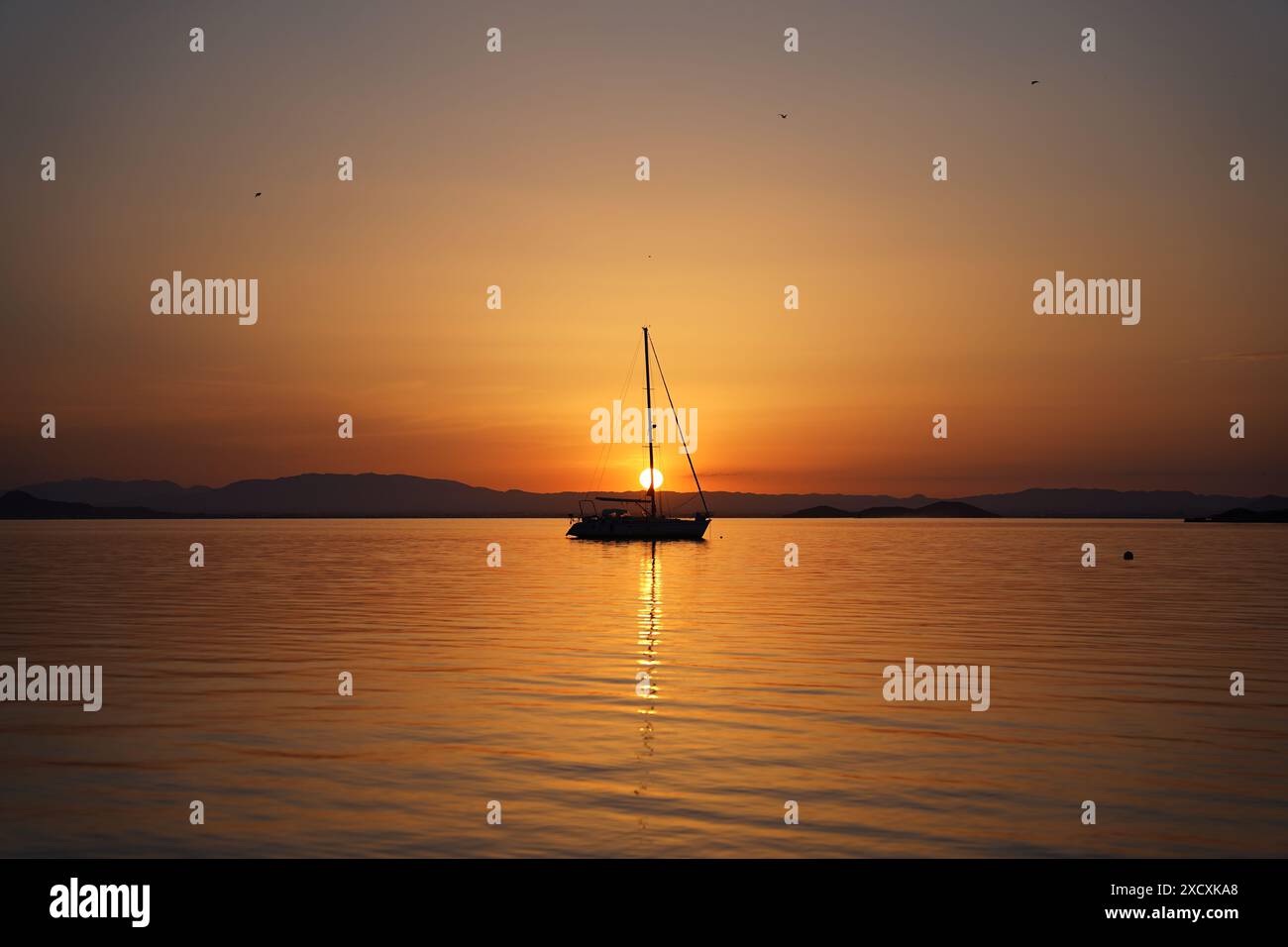 Coucher de soleil en mer avec la silhouette d'un bateau à la Manga del Mar Menor, Murcie, Espagne Banque D'Images