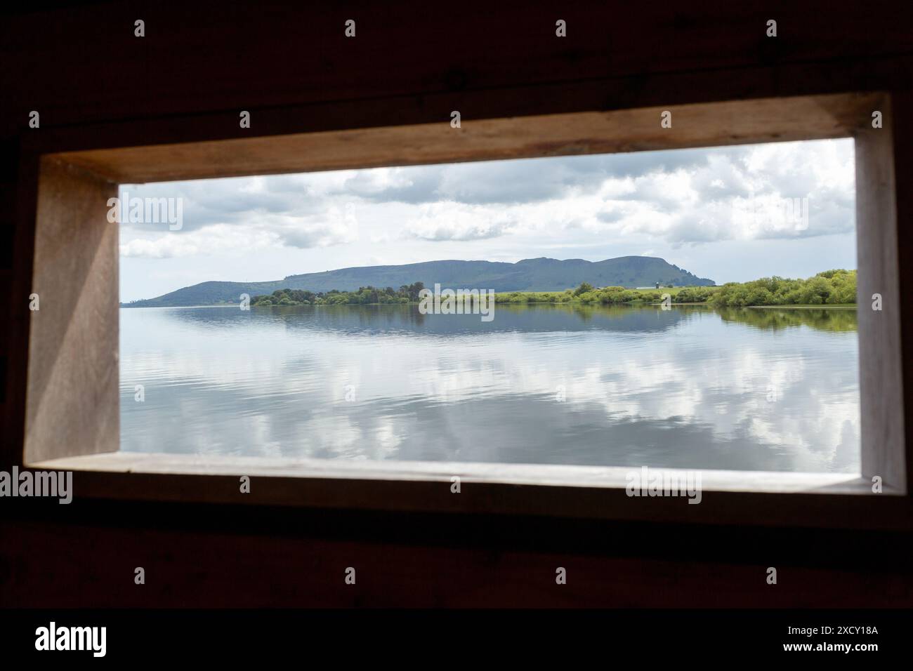 Regardant à travers les eaux calmes du Loch Leven à travers une fenêtre en peau d'oiseau avec Benarty Hill en arrière-plan Banque D'Images