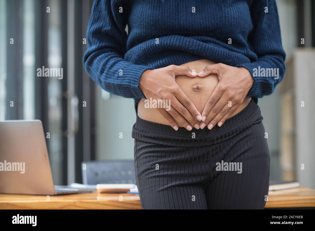 la mère enceinte utilise ses mains pour toucher son estomac pour réconforter bébé à l'intérieur de l'utérus avec tendresse et amour pour le bébé. Une future mère utilise son ha Banque D'Images