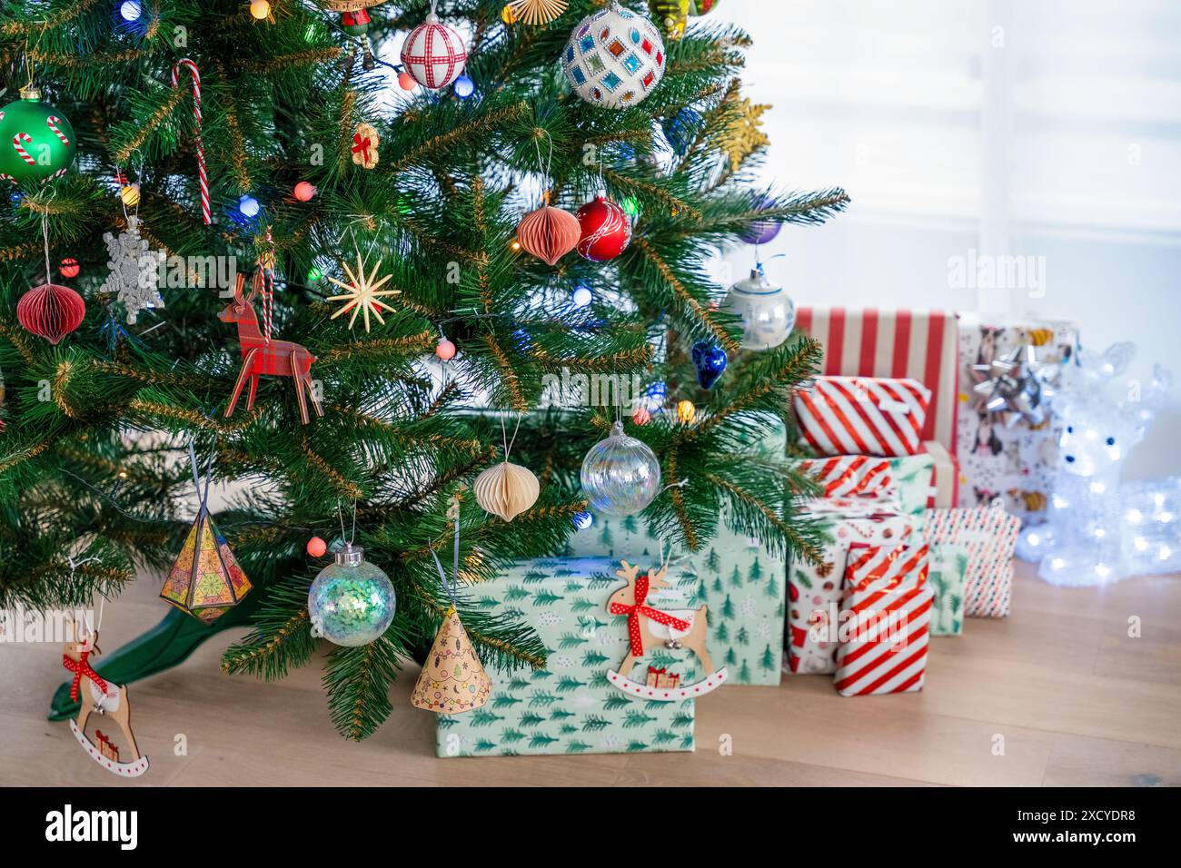 Un arbre de Noël joliment décoré avec divers ornements et cadeaux emballés en dessous. Un cadre intérieur confortable parfait pour la saison des fêtes, feat Banque D'Images