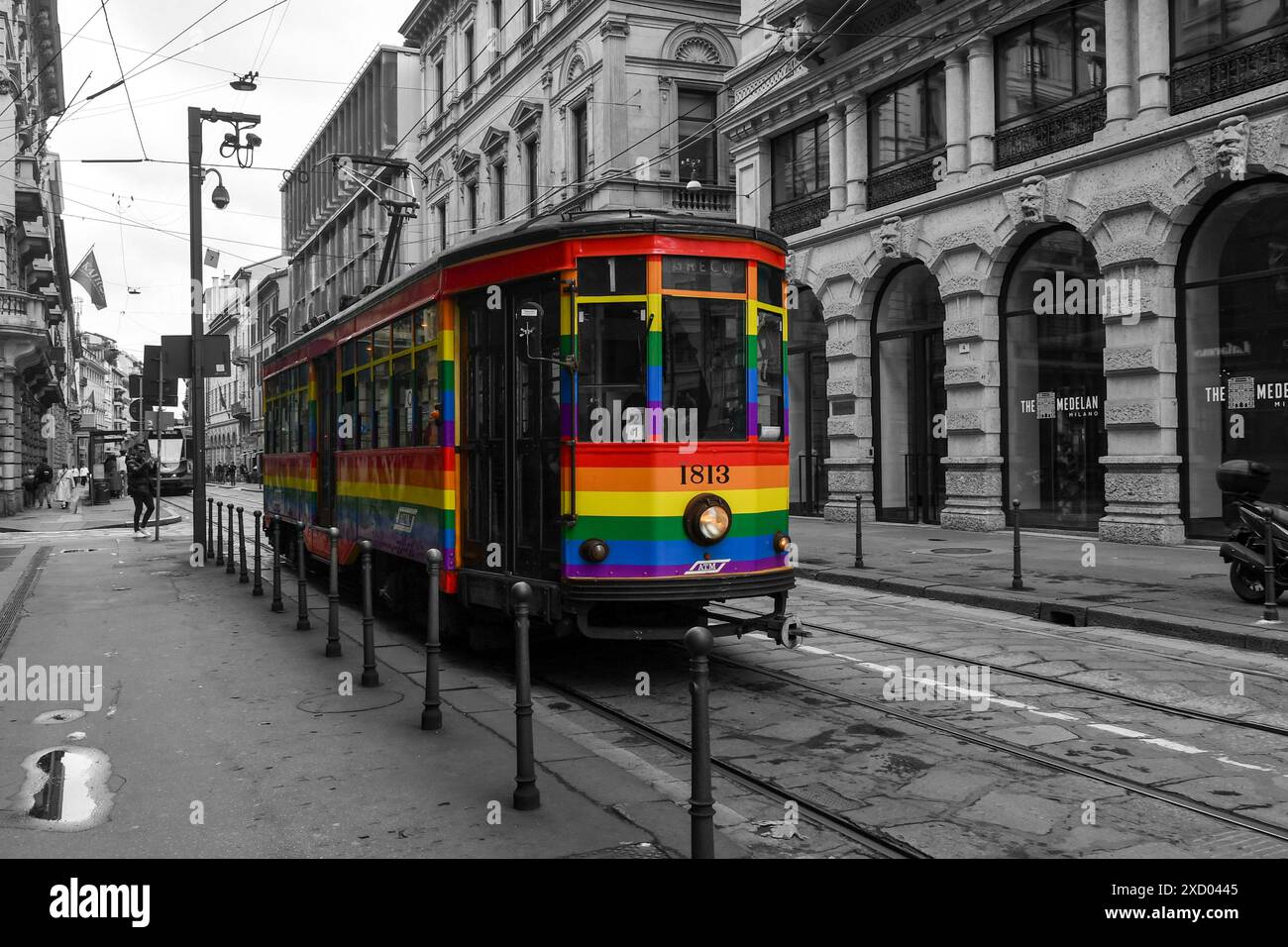 Noir et blanc avec couleur sélective. Ligne 10 tram recouvert du drapeau arc-en-ciel, ou drapeau de fierté, symbole de LGBTQIA+ dans le centre-ville, Milan, Italie Banque D'Images