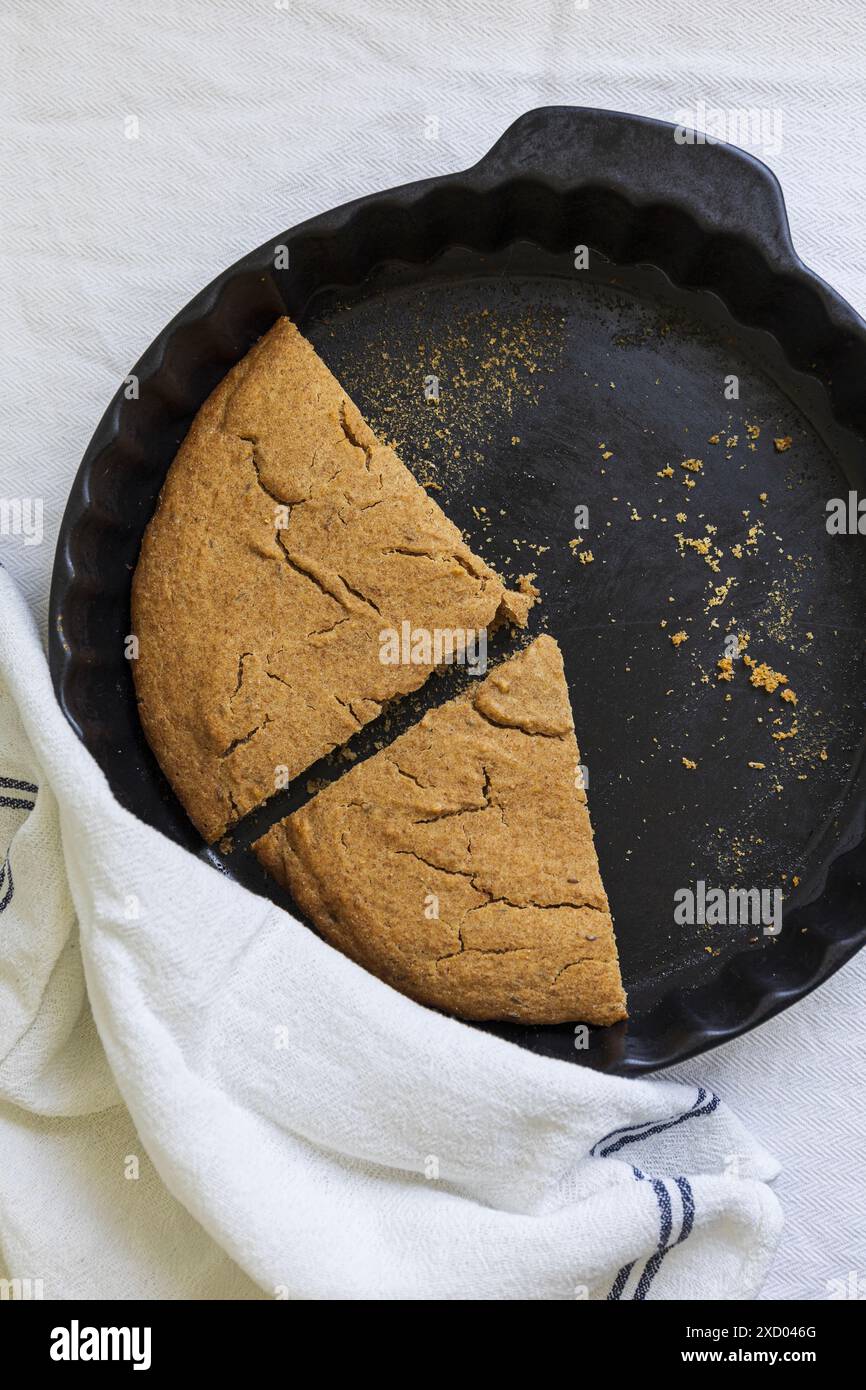 Photographie à plat de Scone d'orge estonien traditionnel (Odrakarask) tranches restantes dans une forme de cuisson en céramique noire avec un torchon de cuisine blanc Banque D'Images
