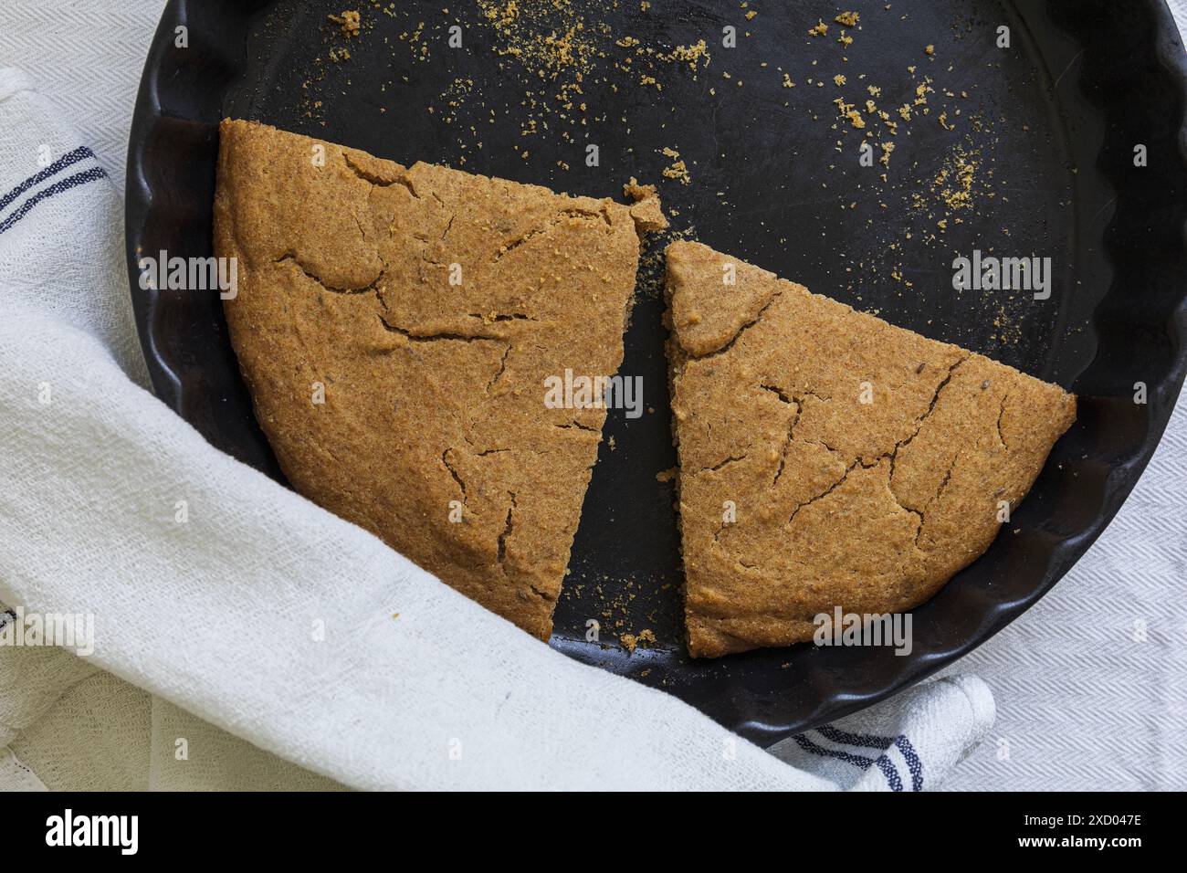 Photographie de table du traditionnel Scone d'orge estonien (Odrakarask) tranches restantes dans une forme de cuisson en céramique noire avec une serviette de cuisine blanche Banque D'Images