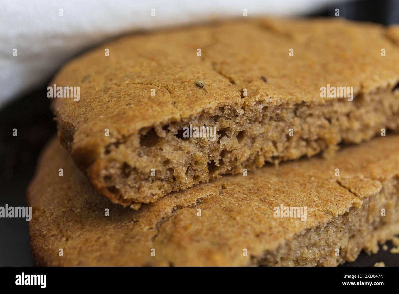 Photographie rapprochée de la texture traditionnelle estonienne Scone d'orge (Odrakarask) dans une forme de cuisson en céramique noire avec une serviette de cuisine blanche Banque D'Images