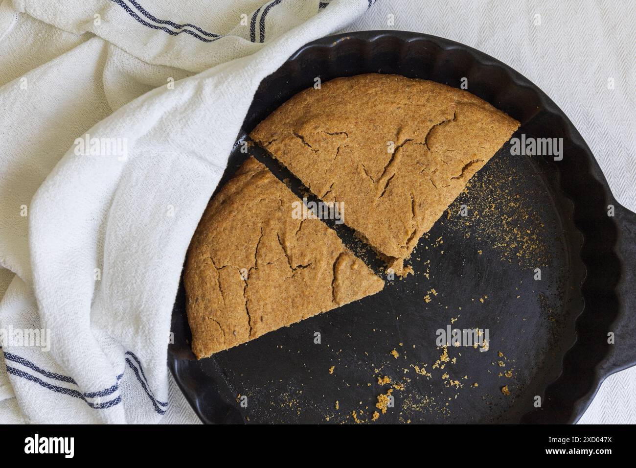 Photographie à plat de Scone d'orge estonien traditionnel (Odrakarask) tranches restantes dans une forme de cuisson en céramique noire avec un torchon de cuisine blanc Banque D'Images