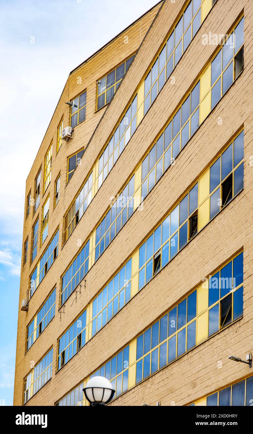 Un bâtiment industriel antique avec une grande façade avec des fenêtres à cadre jaune, mettant en valeur son design architectural historique. Banque D'Images