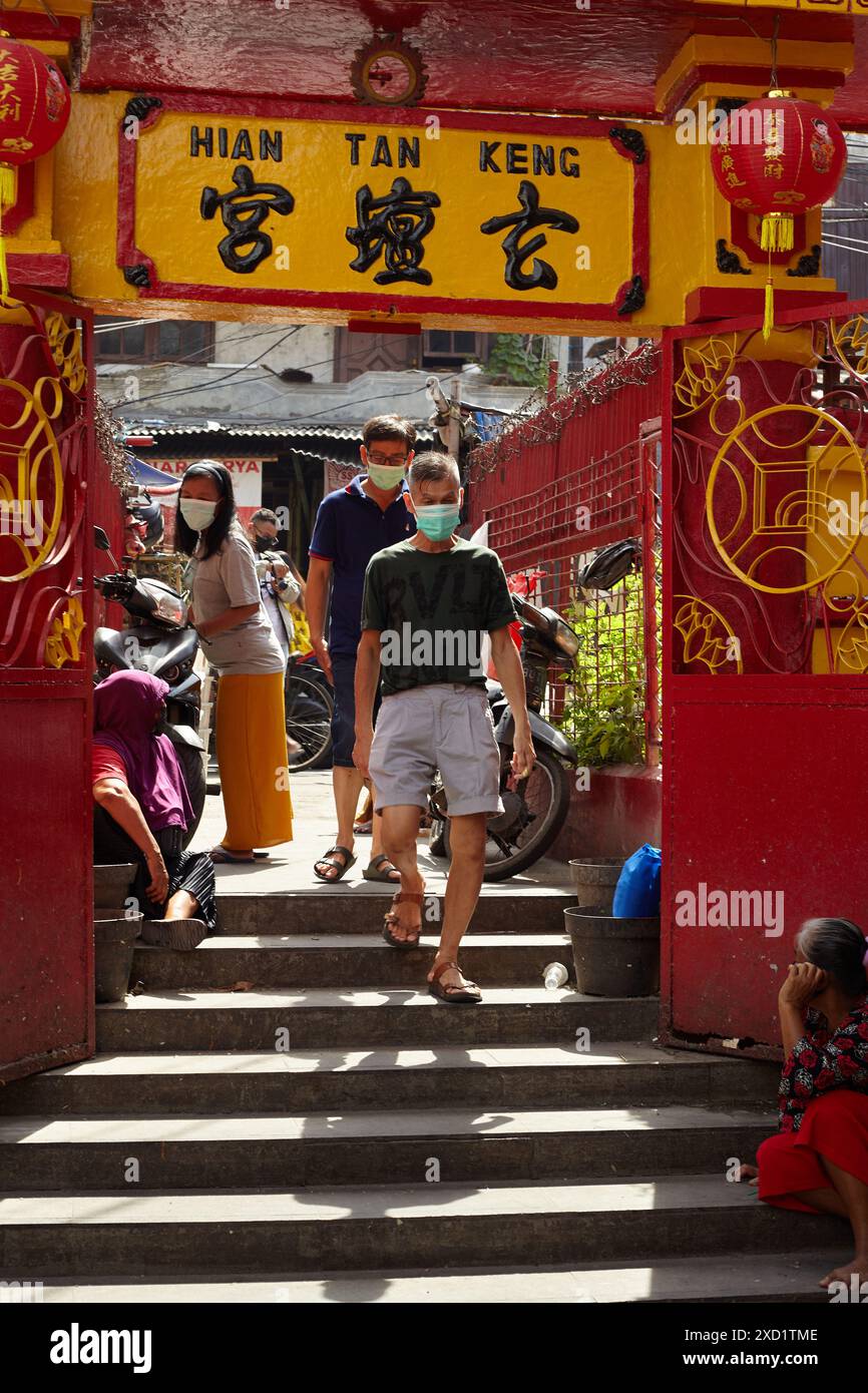 Deux hommes portant des masques entrent dans la porte d'un temple chinois Banque D'Images