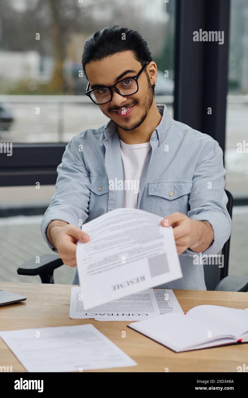 Un homme avec des lunettes tenant soigneusement des documents. Banque D'Images