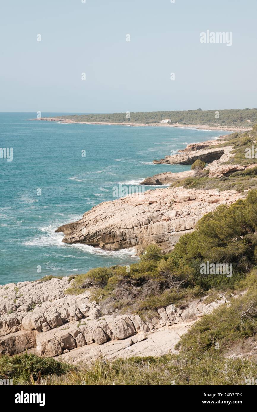 Une scène tranquille d'une plage isolée avec des eaux claires, avec une femme bronzant sur la côte immaculée, entourée par une nature intacte Banque D'Images