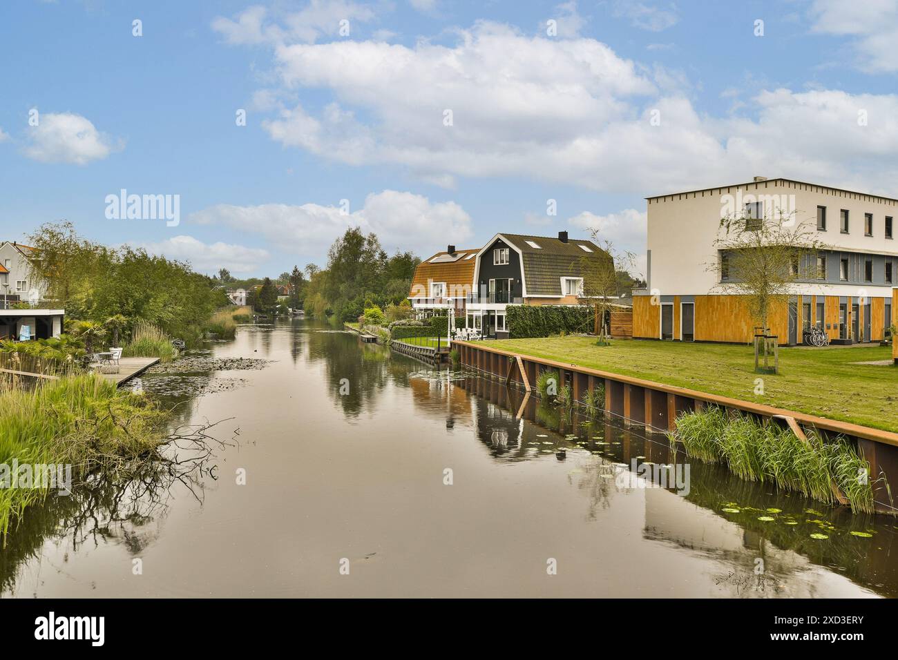 Quelques maisons sur le côté d'un plan d'eau avec des arbres et des buissons à l'avant - une partie de la rivière Banque D'Images