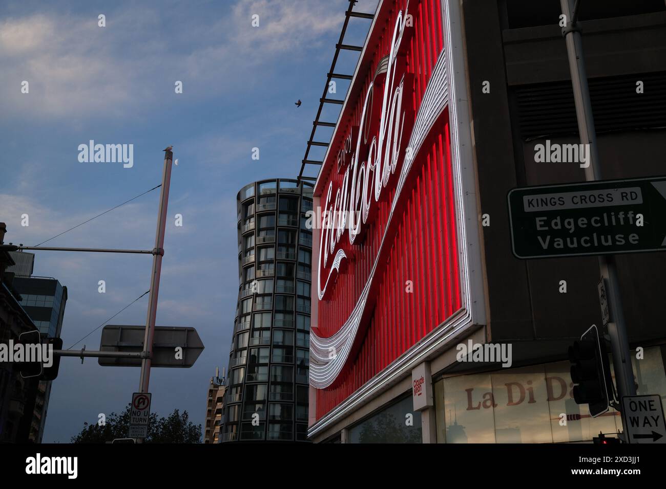 Le panneau Neon, Kings Cross Coca-Cola de près en regardant le long de Victoria St jusqu'à OMNIA immeuble de grande hauteur, illuminé et illuminé Banque D'Images