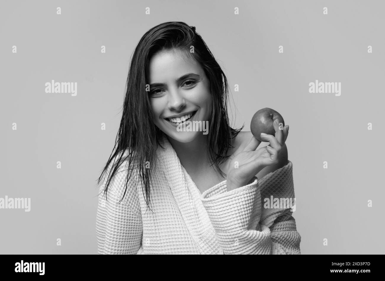 Régime de fruits. Concept stomatologique. Portrait d'une jeune femme joyeuse mangeant une pomme isolée sur fond gris. Femme souriante avec des dents saines tenir Banque D'Images