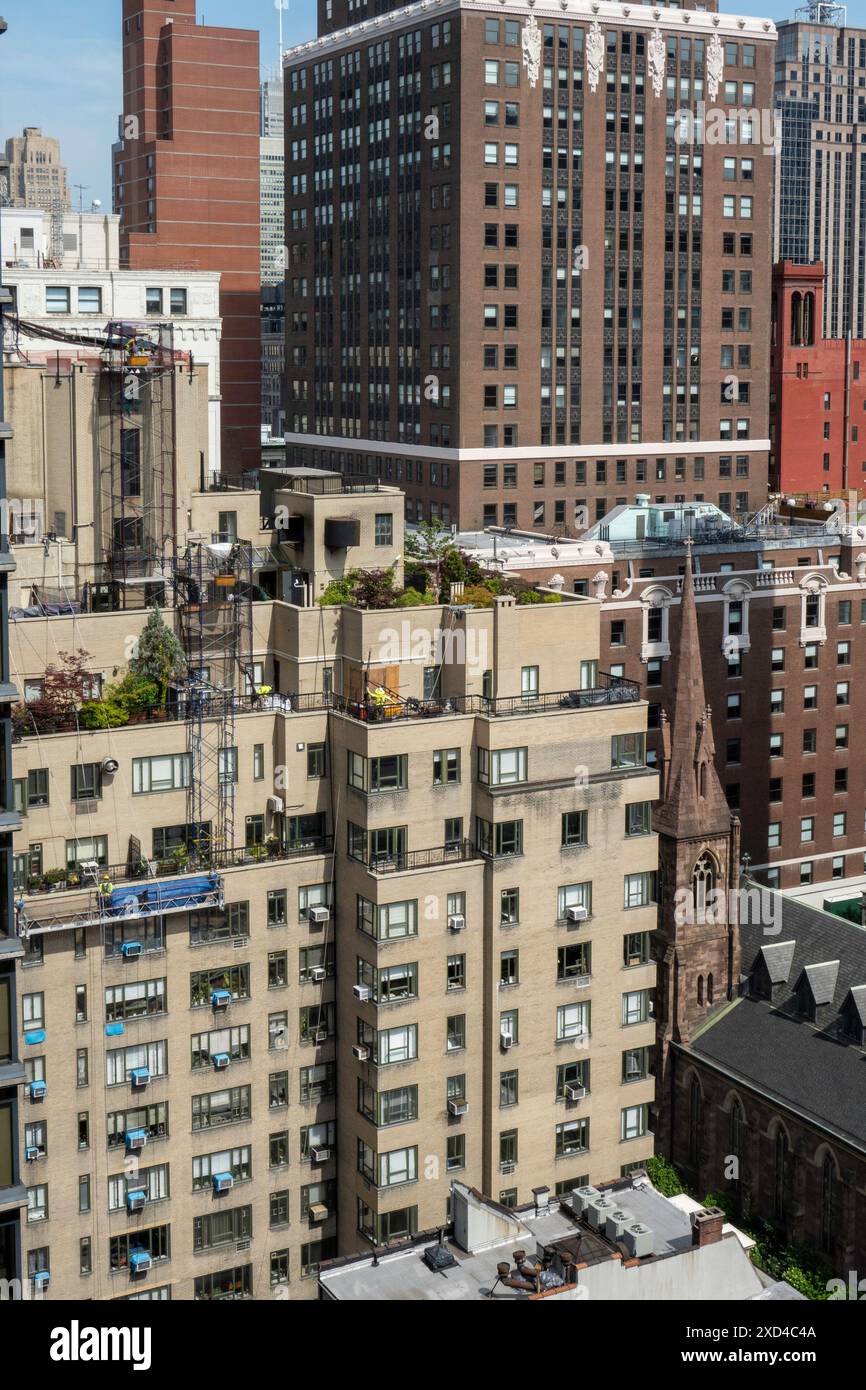 Ouvriers de la construction sur un immeuble d'appartements à New York dans un panier suspendu, Midtown Manhattan, États-Unis 2024 Banque D'Images