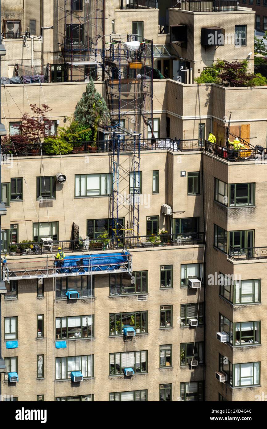 Ouvriers de la construction sur un immeuble d'appartements à New York dans un panier suspendu, Midtown Manhattan, États-Unis 2024 Banque D'Images